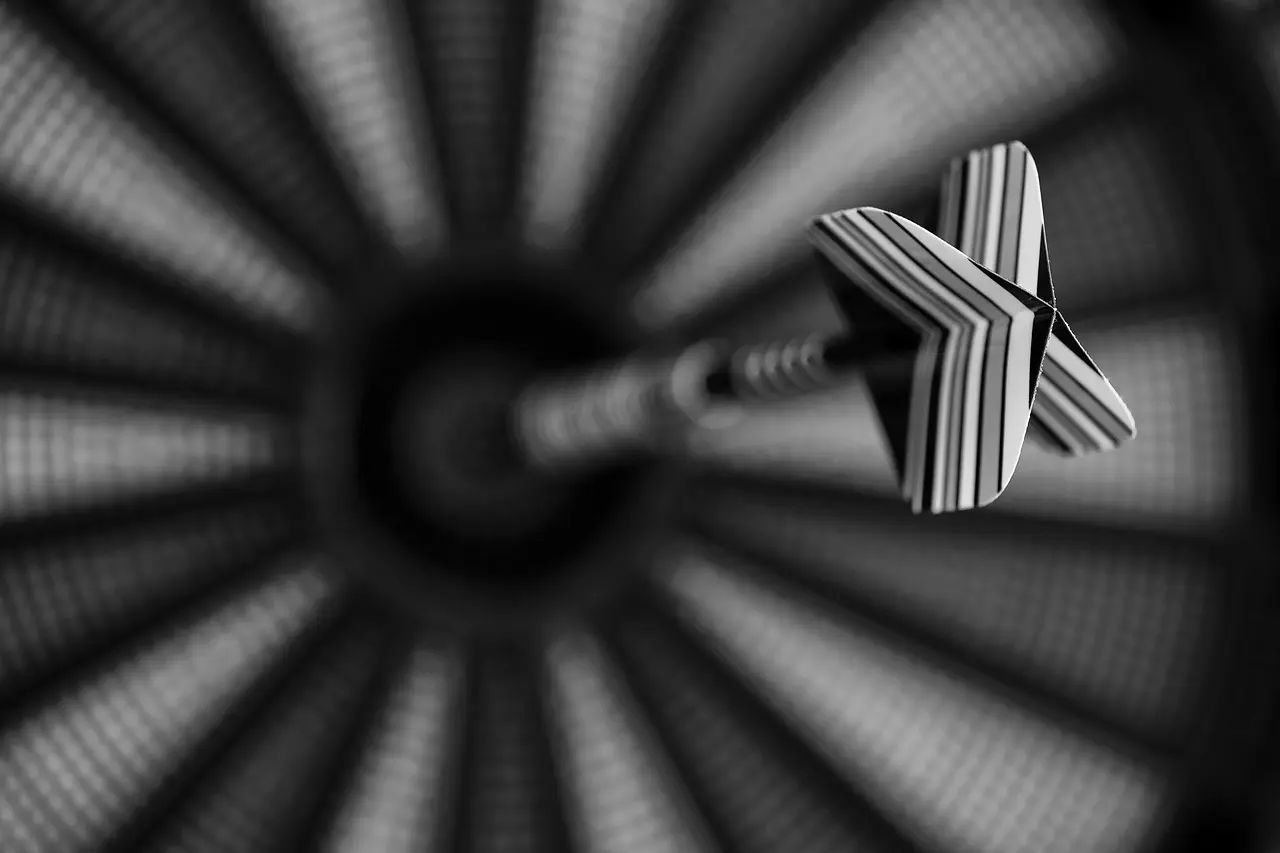 Dartpil med stribet flight foran dartskive