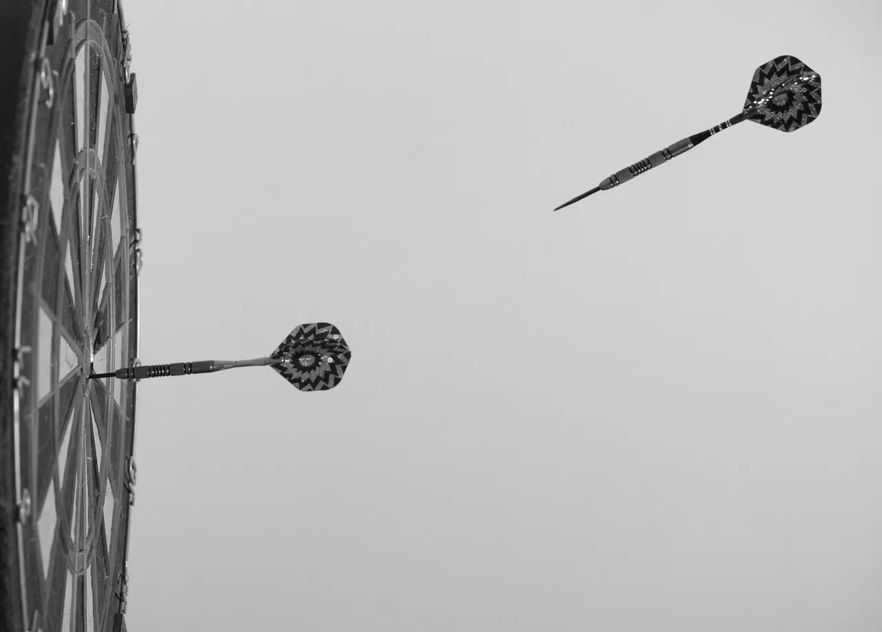 Dartskive med to pile, en i bull's-eye og en flyvende
